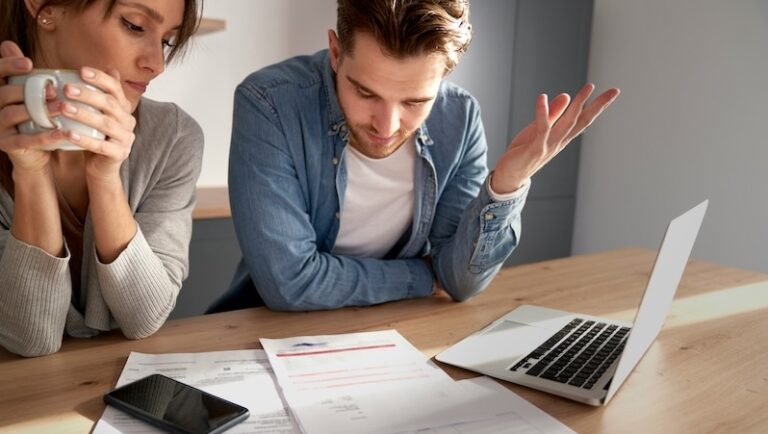 Junges Paar blickt fassungslos auf Brief mit Beitragserhöhung der DKV